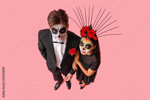Young couple dressed for Mexico's Day of the Dead (El Dia de Muertos) on pink background