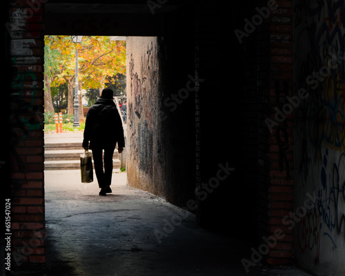 silhouette of an old lady walking outside from a tunnel
