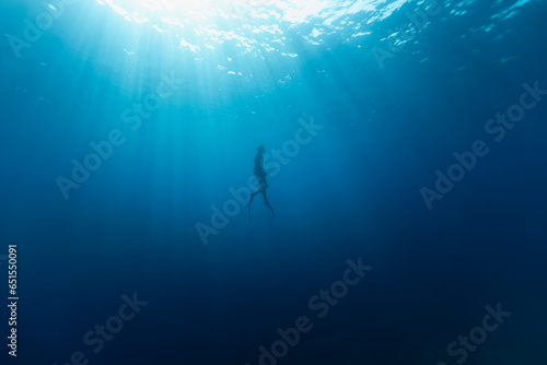 Freediver Swimming in Deep Sea With Sunrays. Young Man DIver Eploring Sea Life. photo