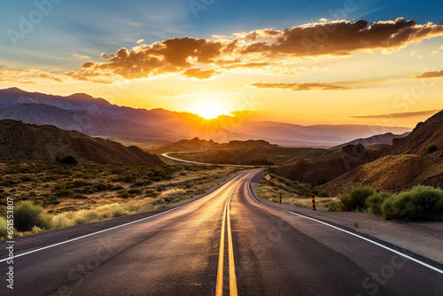 Asphalt road through hilly terrain at sunset.