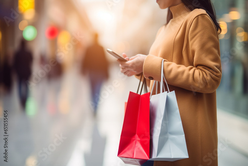 Woman holding shopping colored bags with blurred shops background