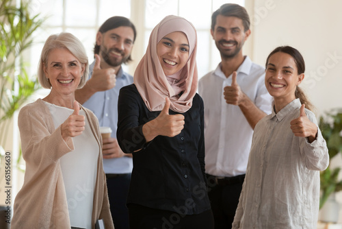 Middle eastern ethnicity woman group leader and millennial middle-aged staff smiling looking at camera showing thumbs fingers up. Best corporate service  career growth  leadership in business concept