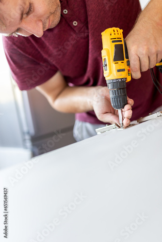 Wallpaper Mural Man using cordless screwdriver machine and screws lie for screwing a screw assembling furniture at home Torontodigital.ca