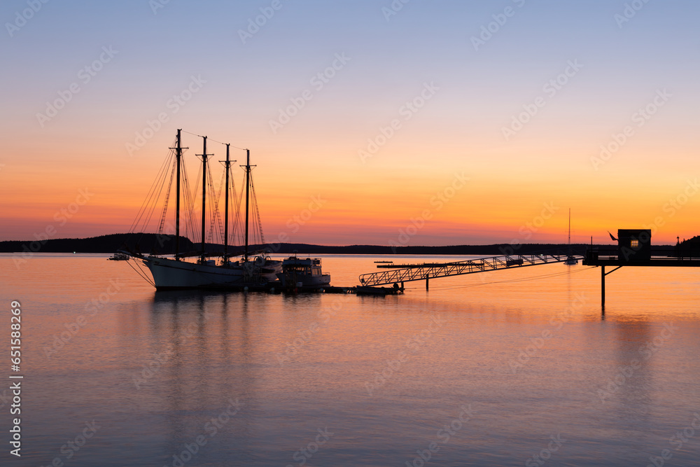 Four-mast sailboat anchored at the pier in Frenchman Bay during a pink and orange sunrise, Bar Harbor, Maine, USA
