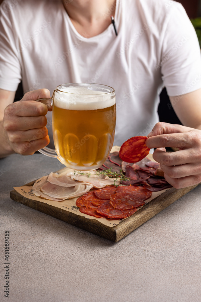 A man holds a glass of beer and a snack. In a restaurant A man holds a glass of beer and a snack. In a restaurant