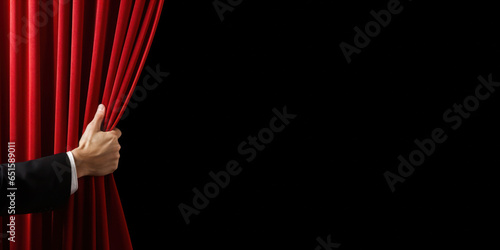 Hand open the red stage curtain. Isolated on black with copy space for text
