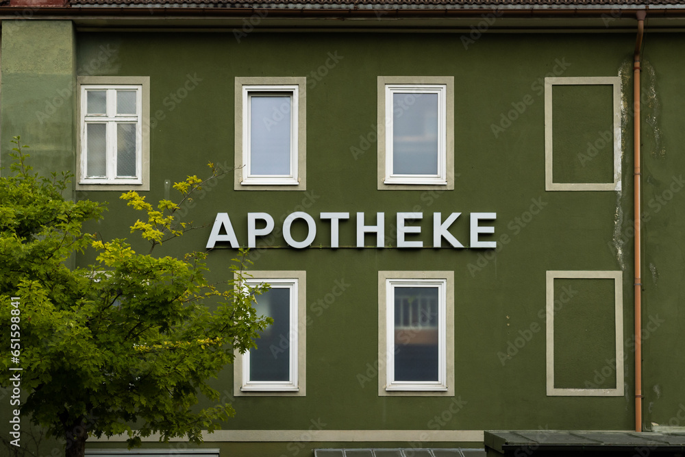 Apotheke sign on an old green building facade. German drugstore house with a weathered exterior. The run down pharmacy store is in a bad condition.