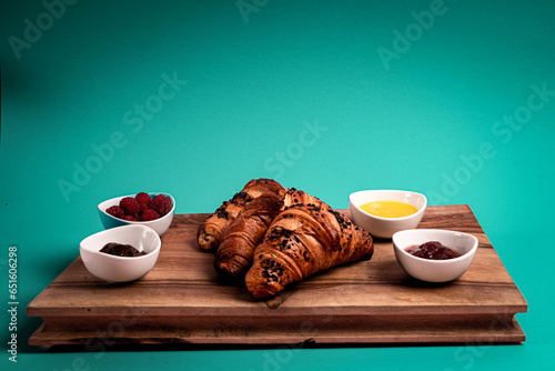 Croissants on the wooden board. Jam, chocolate, raspberries. Perfect French breakfast. Minimalistic photography. 