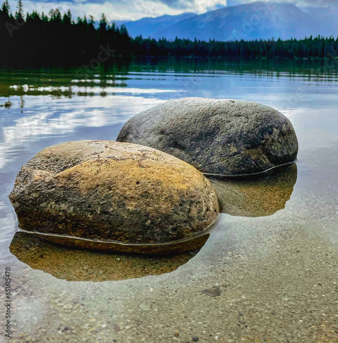 rocks sitting in mountain lake with reflection