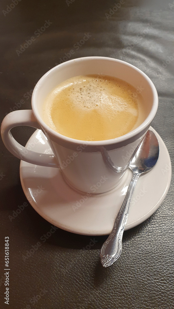 Vertical image of a cup of coffee with a spoon next to it Vertical image of a cup of coffee with a spoon next to it