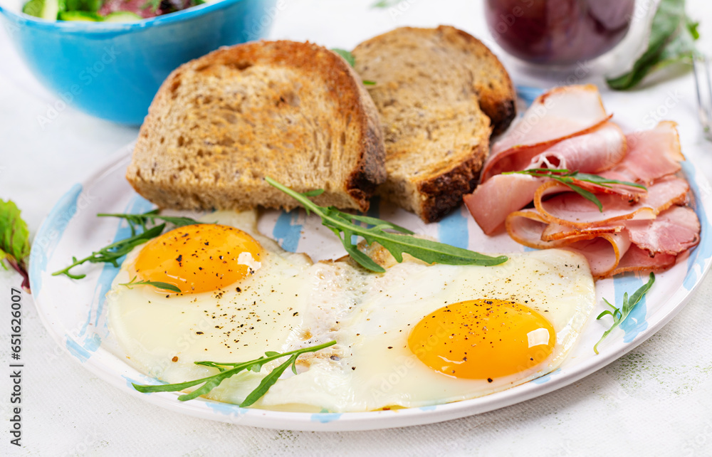 Breakfast. Fried egg, slices of ham and toasted bread. Breakfast. Fried egg, slices of ham and toasted bread.