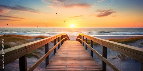 Serene sunset overlooking calm beach. Tranquil beginnings. Peaceful sunrise on ocean shore. Wooden path to paradise. Relaxing beachside boardwalk at dawn