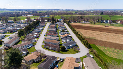 Fototapeta Naklejka Na Ścianę i Meble -  An Aerial View of a Mobile, Modulator, Prefab Home Park, in the Middle of Rural America, with Plowed Fields Next to it, on a Sunny Spring Day