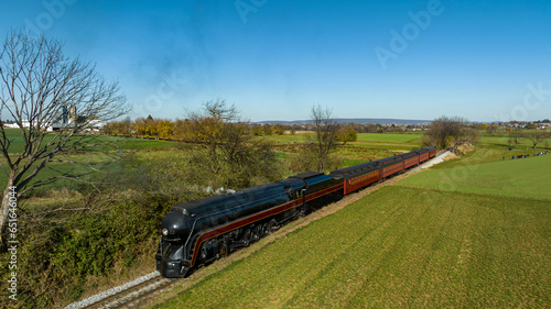 An Aerial View of a Streamlined Steam Passenger Train Traveling Thru Fertile Farmlands on an Autumn Day