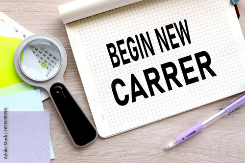Begin new career text on a notebook near a black magnifying glass and a purple sticker
