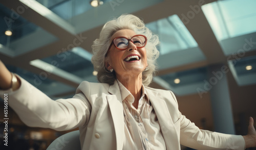 Successful elderly woman in business attire radiates happiness in a business center.