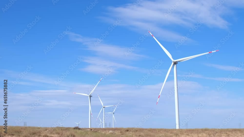 Fleet of power generators in motion. The blades of the wind farm rotate against the sky. The concept of extracting electricity from renewable sources. Wind turbine to generate electricity. Fleet of power generators in motion. The blades of the wind farm rotate against the sky. The concept of extracting electricity from renewable sources. Wind turbine to generate electricity.