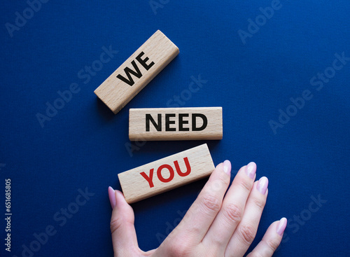 We need you symbol. Concept words We need you on wooden blocks. Beautiful blue background. Businessman hand. Business and We need you concept. Copy space.