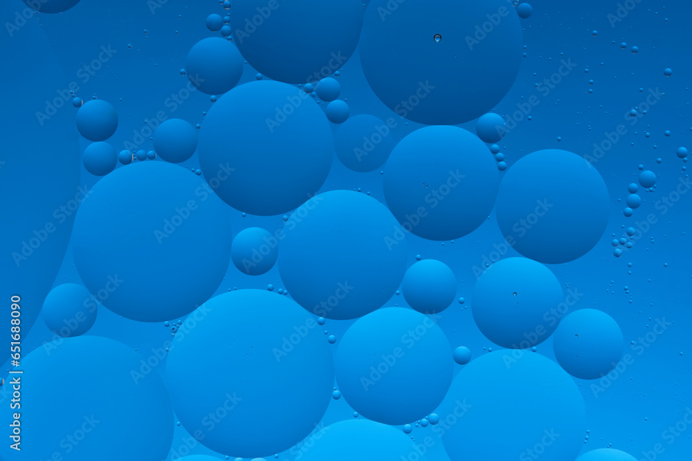 Macro photo with circles oil droplets water surface. Abstract blue background with oil bubbles.