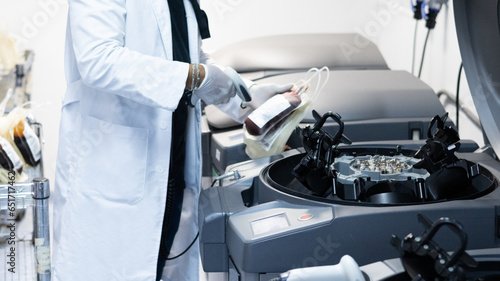 Técnico varón de aspecto latino usando guantes y escaneando una unidad de sangre entera para su fraccionamiento a través de un equipo automatizado moderno y seguro.