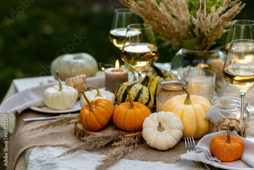 Autumn cozy mood table composition for family thanksgiving dinner with wine  pumpkins  candles on wooden tray. Fall mood  warm plaid. Hygge home decor  interior seasonal design