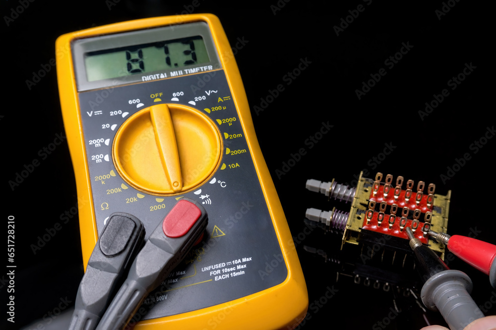 Electronics, close-up of a digital multimeter with its tips measuring the status of a combination switch