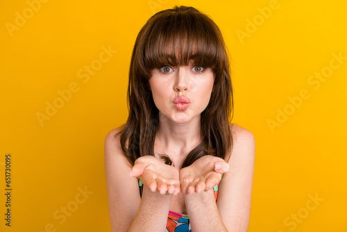 Photo of flirty sweet lady wear flower print clothes sending arms kiss isolated yellow color background