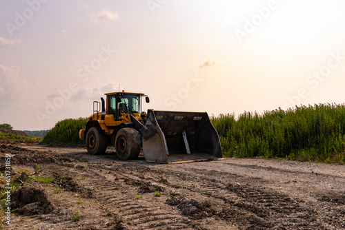 Yellow bulldozer - parked on dirt road - rural area with field and trees. Taken in Toronto, Canada.