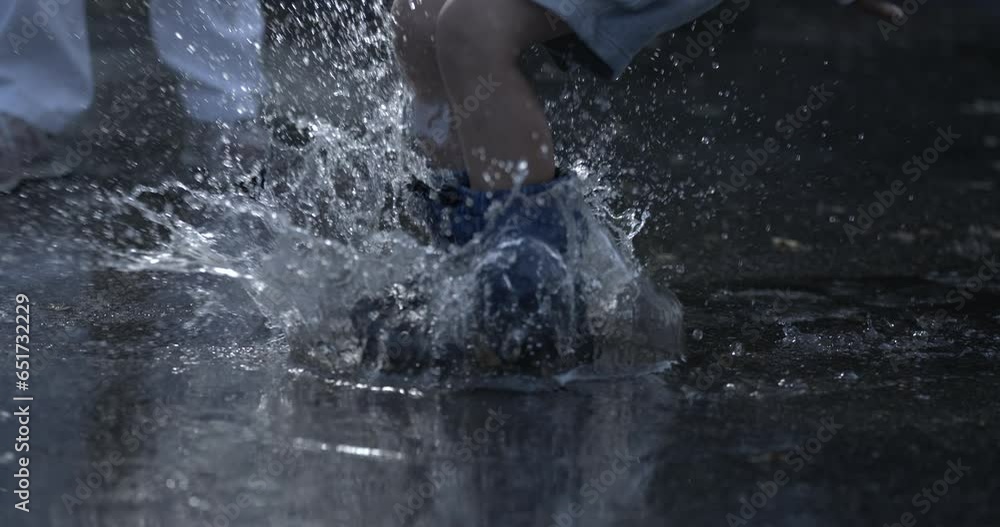 Playful Child feet jumping into water puddle in slowmotion splashing