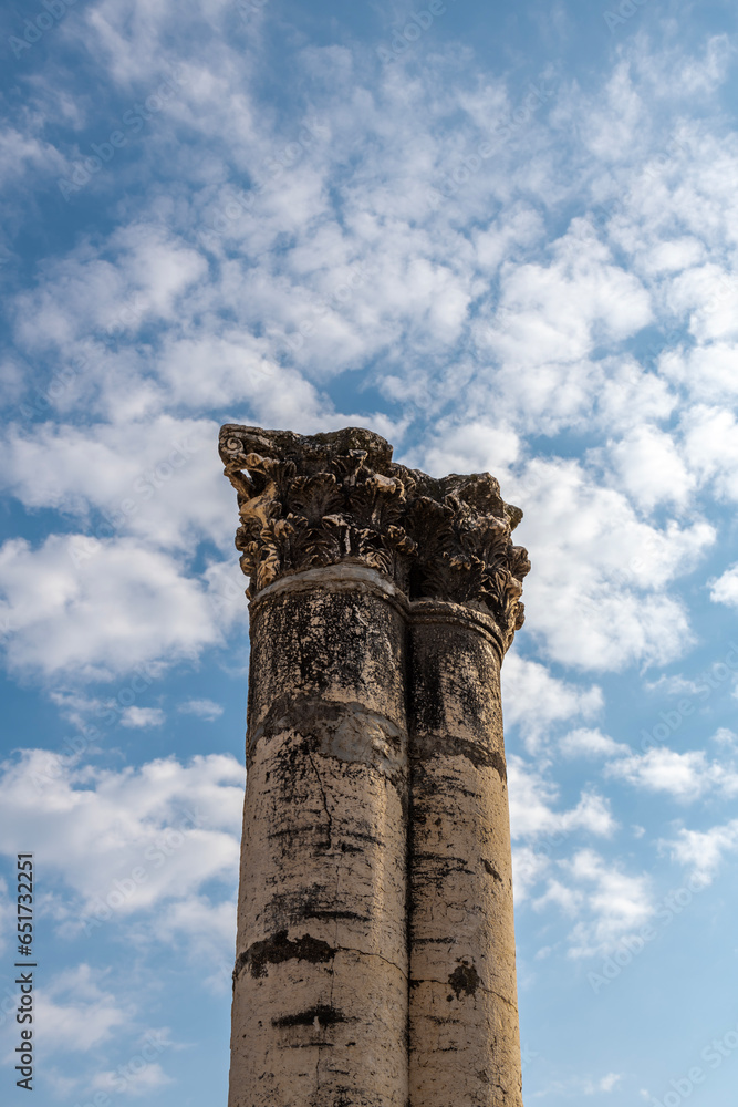 Two columns with capitals against a blue sky with white clouds at Capernaum, Kfar Nahum, Capharnaum in Israel
