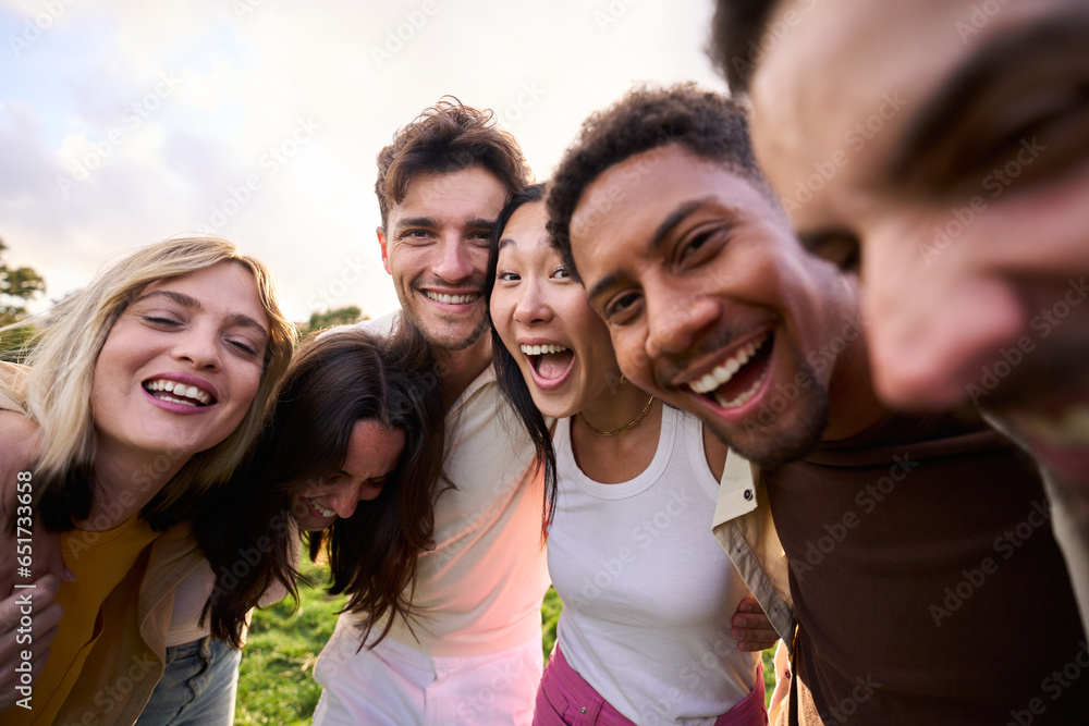 Fototapeta premium Crazy selfie of a group of young multirracial people embracing. Exited friends enjoying leisure and laughing a lot looking at camera outdoors. Diverse guys and girls community celebrating together