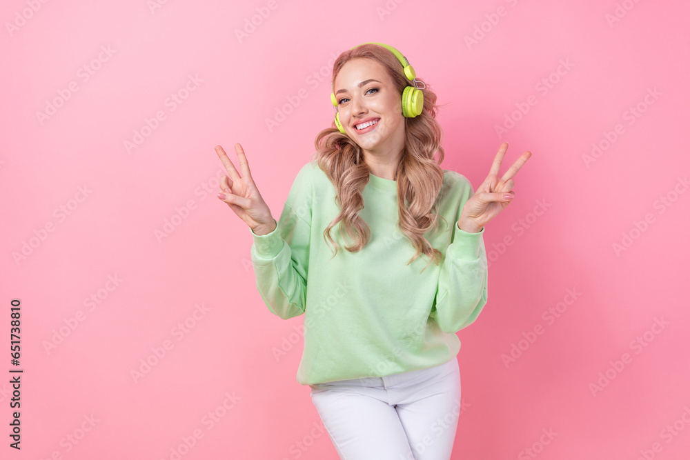 Portrait of woman dancing two hands v sign demonstrate her peace chill listen wireless headphones apple isolated on pink color background