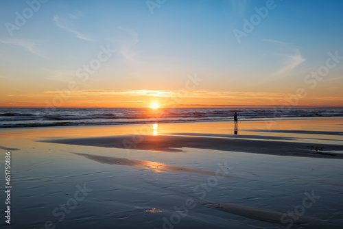 Atlantic ocean sunset with photographer silhouette taking images of surging waves at Fonte da Telha beach  Costa da Caparica  Portugal