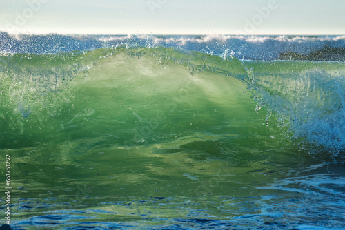 Canvas Print Breaking ocean wave on sunset backlit with sun
