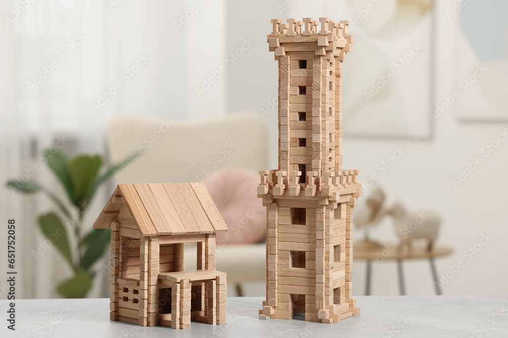 Wooden tower and house on light grey table indoors. Children's toys