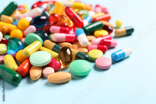 Many different pills on light blue background, closeup. Space for text