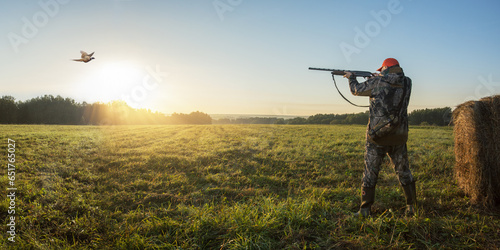 Hunting for a pheasant at autumn field. hunter shooting into flying pheasant at sunrise. hunting banner
