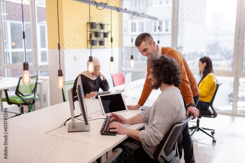 Business people having conversation in front of a computer. Modern multiethnic coworking office space.