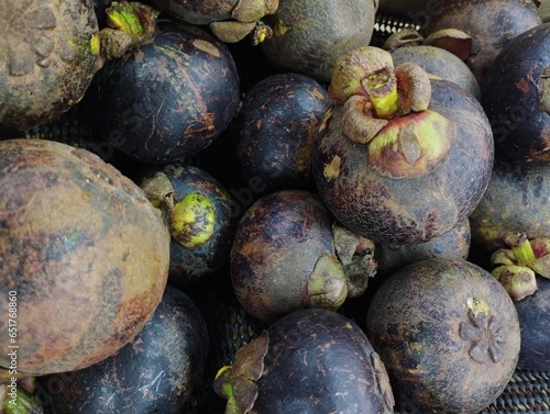 close up photo of a pile of mangosteen or Garcinia Mangostana Linn in a supermarket display case, fresh fruit ready to be sold to meet your body's needs