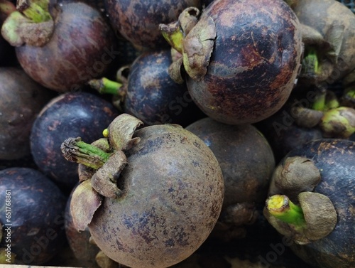 close up photo of a pile of mangosteen or Garcinia Mangostana Linn in a supermarket display case, fresh fruit ready to be sold to meet your body's needs