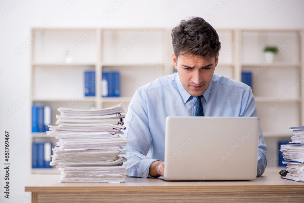 Young male employee and too much work in the office Young male employee and too much work in the office