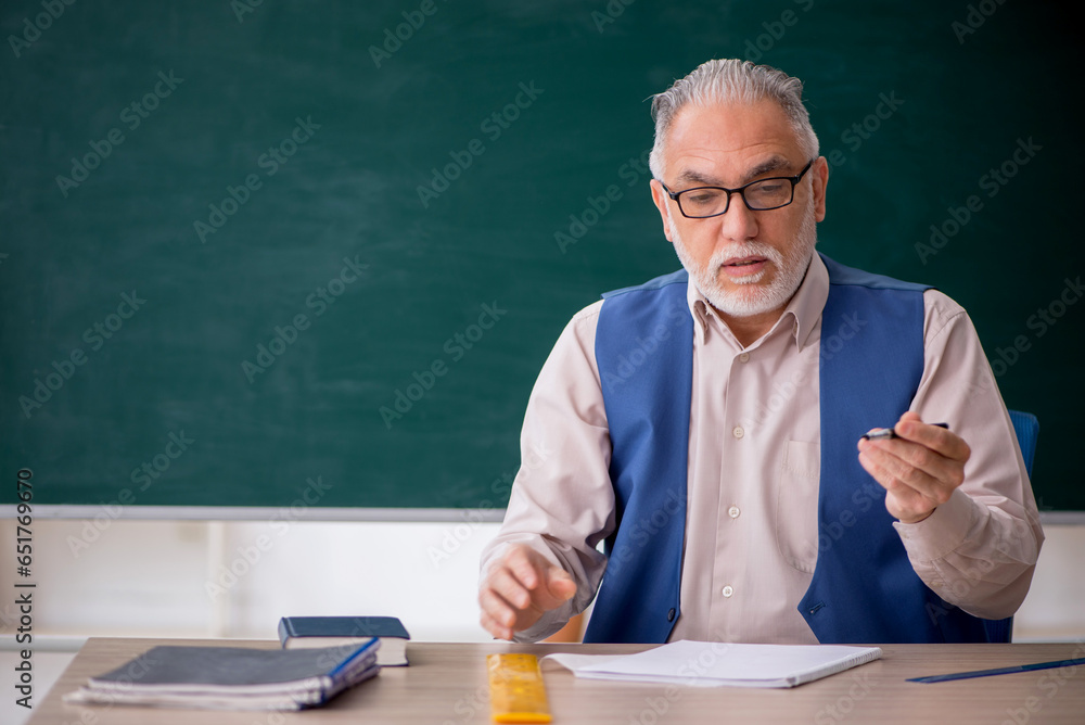 Old male teacher in front of green board Old male teacher in front of green board