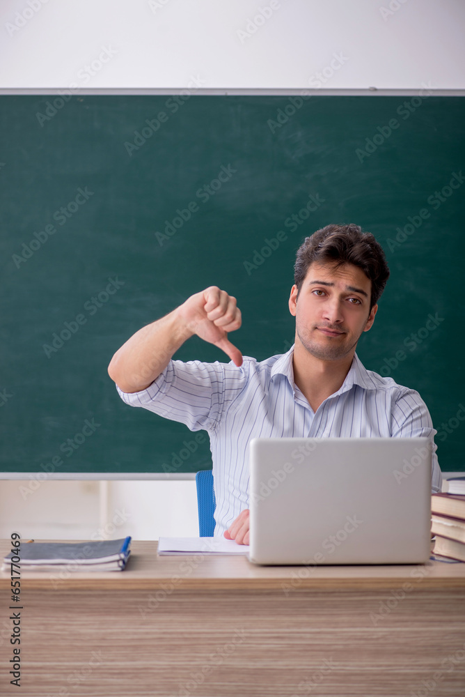 Young male teacher in front of green board Young male teacher in front of green board