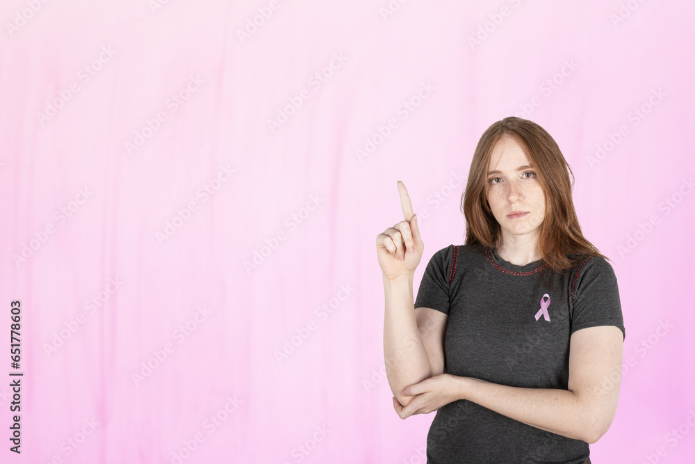 Woman wearing a pink breast cancer awareness ribbon. Concept of struggle with breast cancer Woman wearing a pink breast cancer awareness ribbon. Concept of struggle with breast cancer