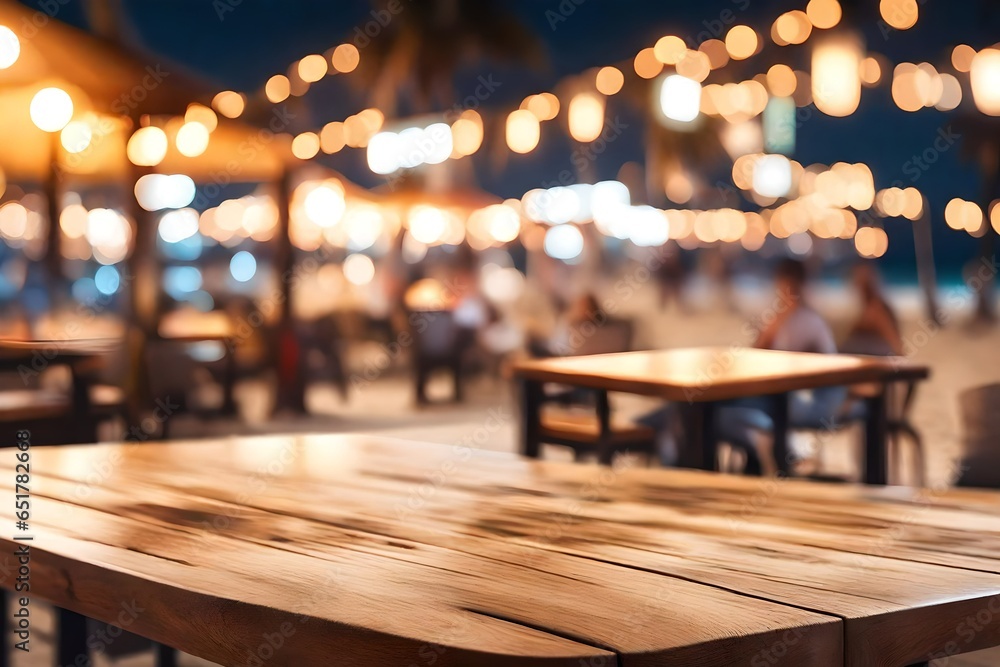 Wooden table with blur beach cafes background and bokeh lights .