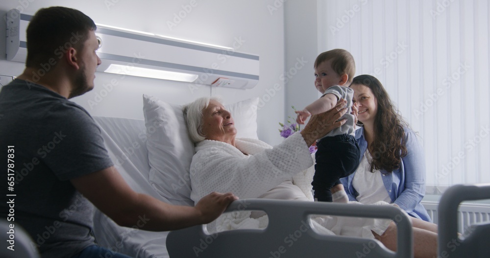 Female elderly patient lies in bed in bright hospital ward, plays with little grandson. Loving family members support senior woman recovering after successful surgery. Modern medical facility. Female elderly patient lies in bed in bright hospital ward, plays with little grandson. Loving family members support senior woman recovering after successful surgery. Modern medical facility.