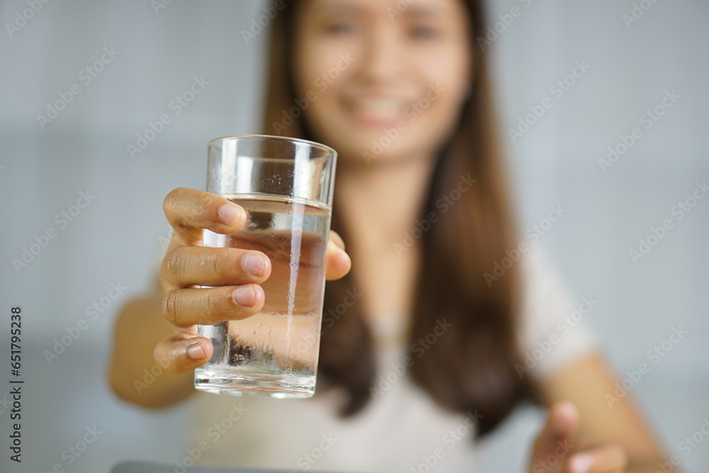 Asian woman working at home holding a glass of water in hand Asian woman working at home holding a glass of water in hand