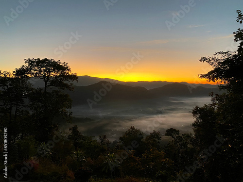 Sunrise behind mountain in the morning with magnificent mist landscape in winter season.