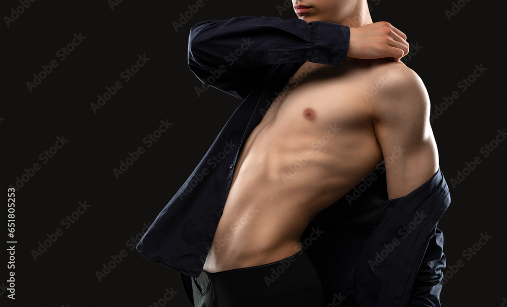 Obraz premium Handsome sexy man with a pumped up body in a dark shirt on a black background. Sports and healthy lifestyle.