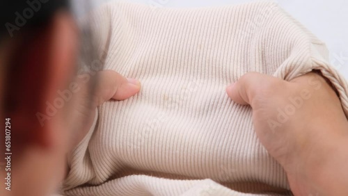 Close-up of woman looking at dirty stains on child's unwashable shirt. Dissatisfied young woman showing stains on t-shirt. Laundry problems